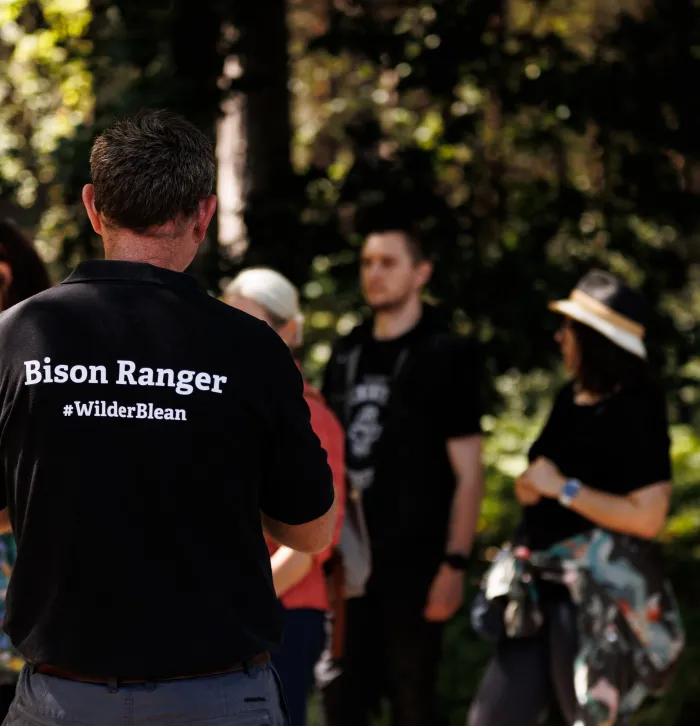 A ranger talking to a group in woodland, Bison Ranger #Wilder Blean can be seen on his uniform.