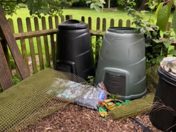 Two water butts in the corner of a garden