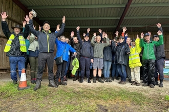 A group of volunteers for Kent Wildlife Trust cheering in a barn