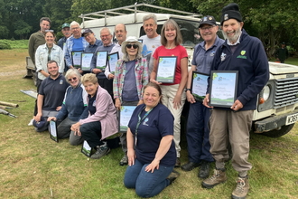 A group of Ashford Kent Wildlife Trust volunteers standing with their Wilder Kent Award certificates.