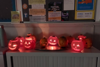 A row of carved pumpkins sat on top of a cabinet, with candles in them.