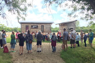 A group of people stood outside wooden buildings at Tree of Life Veganic Farm