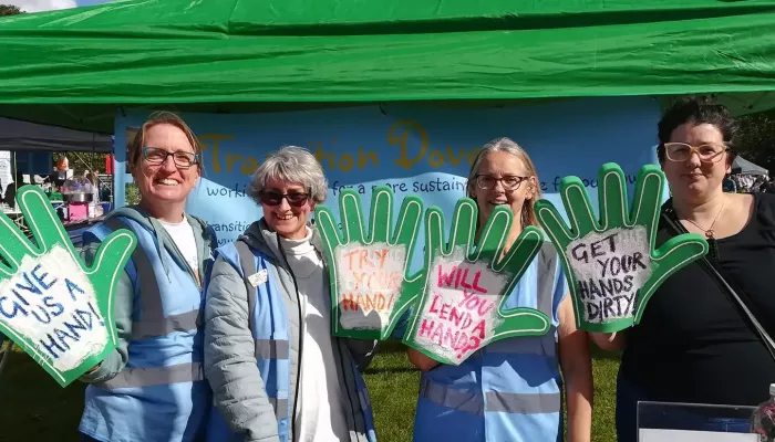 Members of the community group transition dover standing at a stall with foam hands promoting gardening