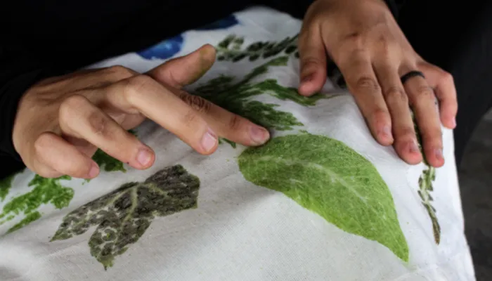Hands on fabric printed with green leaf shapes