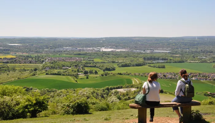 Two people sitting on a bench looking out over the views at Blue Bell Hill