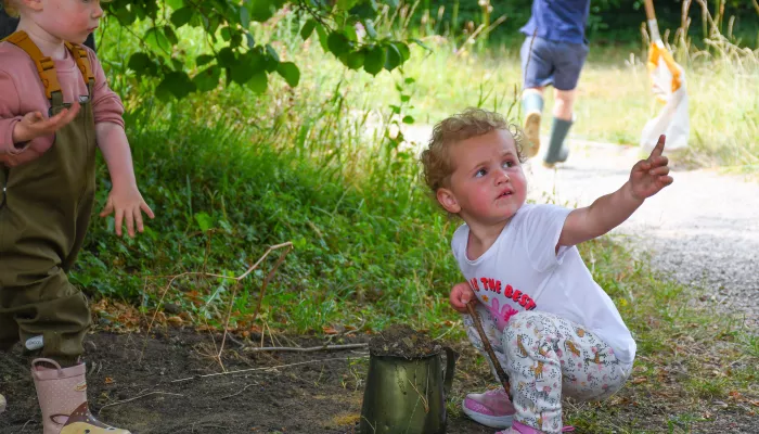 Nature tots toddler playing and looking up at parent