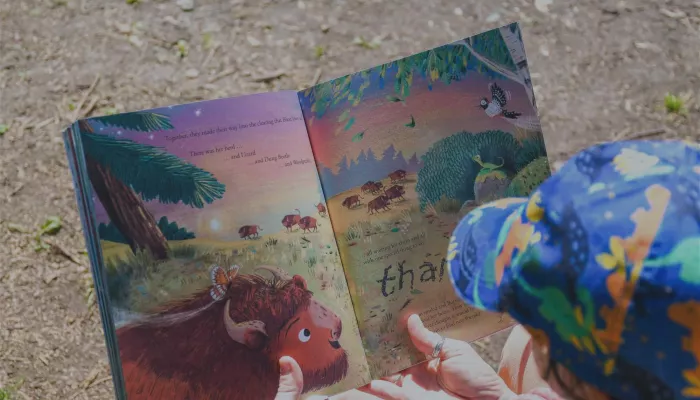 Someone holding open a book and reading it to a child.