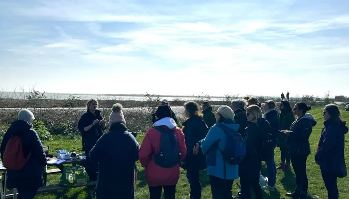 Women standing in the sunshine on a nature reserve listening to the ranger