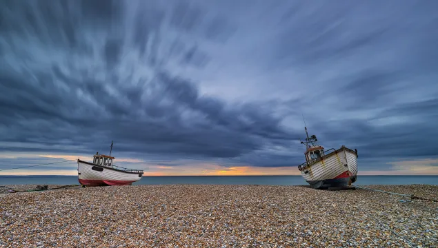 Sunrise at Dungeness with two boats on the shingle in low tide