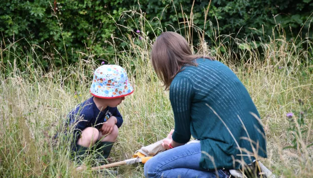 Adult with child kneeling on the grass and learning about wildlife at Nature Tots by Tim Horton