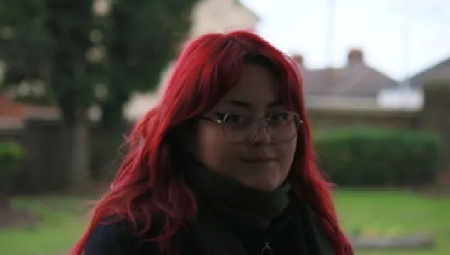 Our nature hero Aimee Howe, with red hair standing in front of a tree.