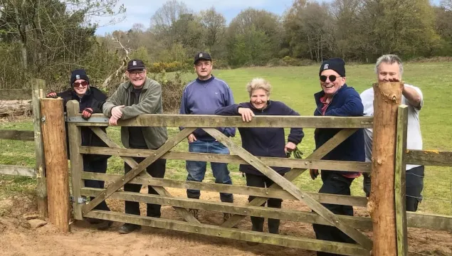The Ashford volunteering gang standing by a gate and smiling.