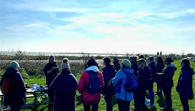 Women standing in the sunshine on a nature reserve listening to the ranger