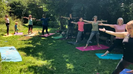 A group of people practicing yoga on the grass outside