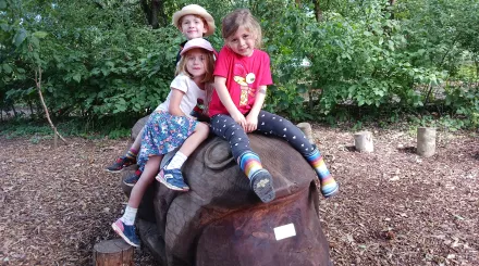 Kids sitting on wooden frog sculture when taking part in Wilder Holiday Club