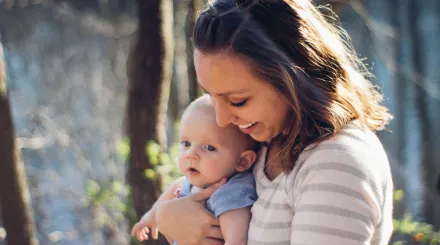 parent with young baby in nature smiling 