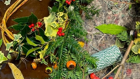 Evergreen foliage, berries and string with willow branched woven into a wreath