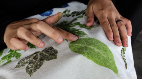 Hands on fabric printed with green leaf shapes