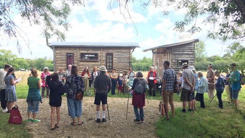 A group of people stood outside wooden buildings at Tree of Life Veganic Farm