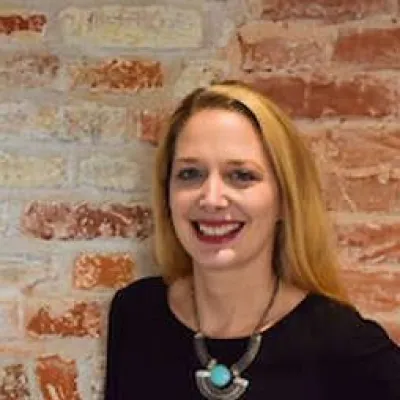 Hollie Du Preez, Deputy Director (Strategic Conservation Initiatives) at KWT smiling in front of a brick wall.