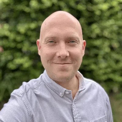 Lee Mason-Baldwin, Deputy Director (Education & Engagement) at KWT, smiling in front of a green backdrop.