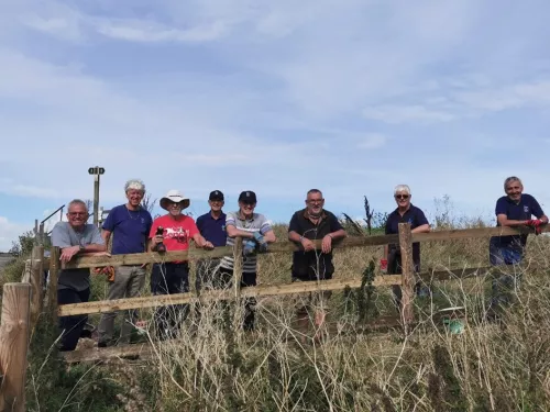 Group of volunteers standing behind a fence at Oare marshes