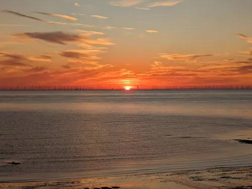 Sunset on water with wind turbines in distance