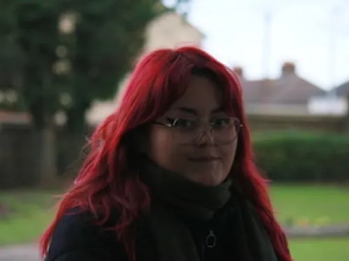 Our nature hero Aimee Howe, with red hair standing in front of a tree.