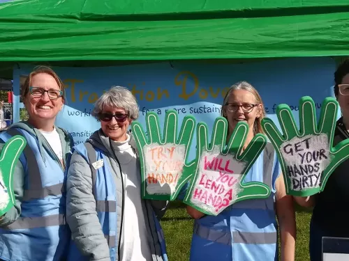 Members of the community group transition dover standing at a stall with foam hands promoting gardening