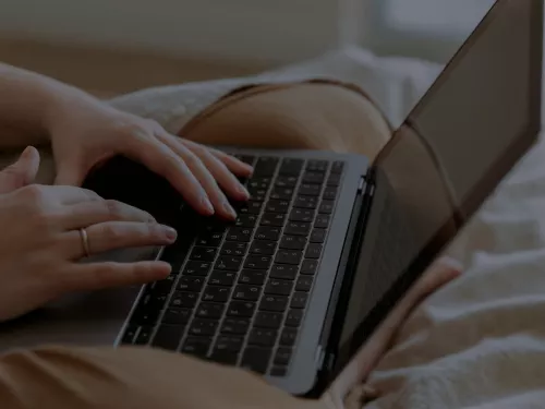 A person sat on a bed using their laptop.