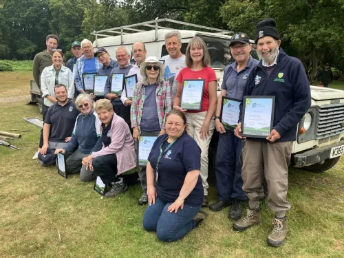 A group of Ashford Kent Wildlife Trust volunteers standing with their Wilder Kent Award certificates.