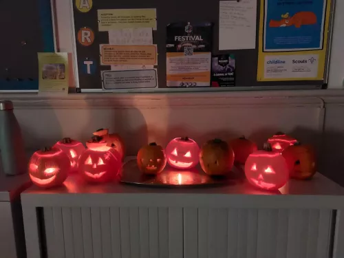 A row of carved pumpkins sat on top of a cabinet, with candles in them.