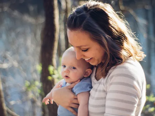 parent with young baby in nature smiling 