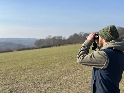 Hoathly Farm image man looking at landscape with binoculars 