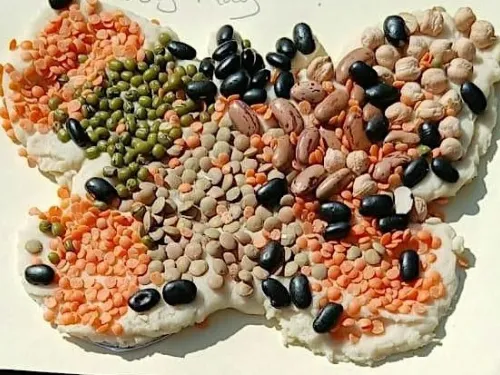 A butterfly shape made from salt dough, decorated with  mix of coloured seeds and beans