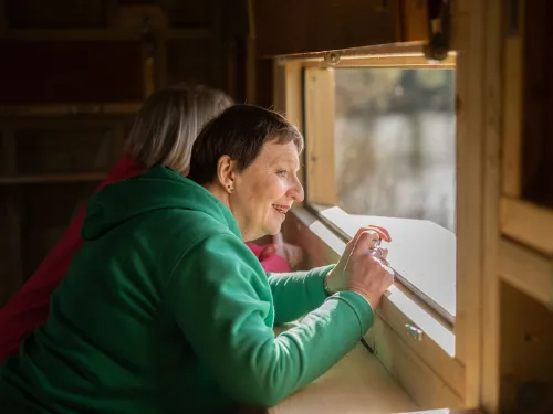 Two people looking out of the window of a bird hide