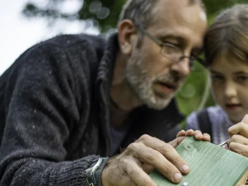 A man and a young girl building a wildlife home together
