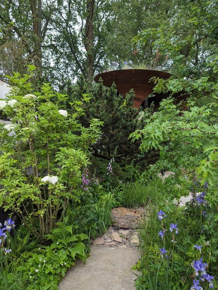 A path and metal structure amongst greenery at Chelsea Flower Show