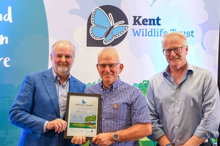 Dennis Fryer, standing with a Wilder Kent Volunteer Award certificate.