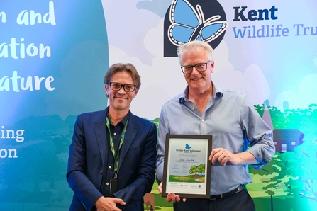 Rob Smith, standing with a Wilder Kent Volunteer Award certificate.