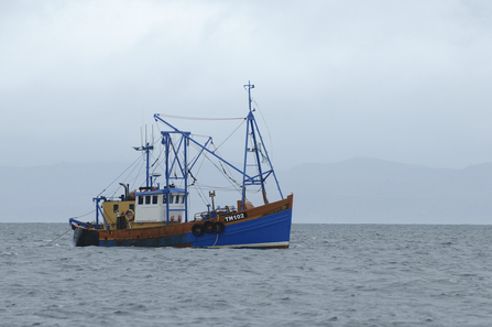 A fishing boat out at sea on a grey day.