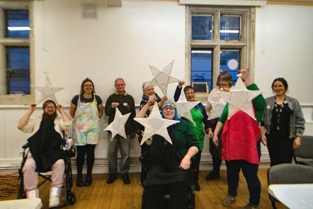 People standing in a hall with stars they have made.