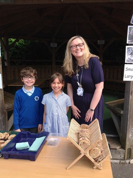 Two children and their teacher standing by a fundraising stall